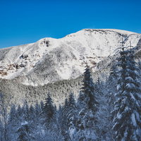冬の赤岳山頂標識と八ヶ岳連峰の断崖の写真