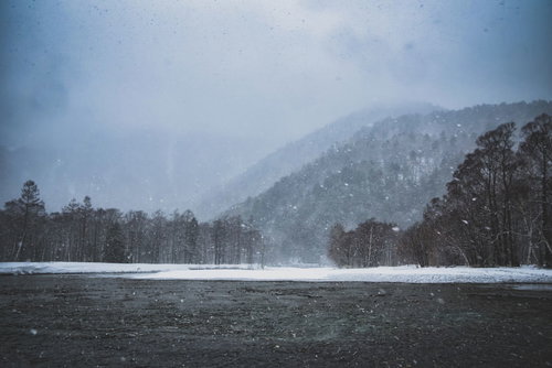 吹雪く梓川と雪化粧の山々（上高地）