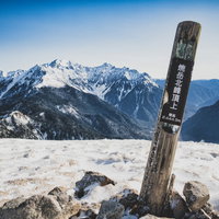 北アルプス焼岳山頂の指導標と雪化粧した山々の写真