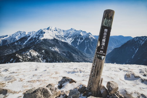 北アルプス焼岳山頂の指導標と雪化粧した山々