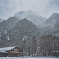 吹雪で視界不良の上高地バスターミナルと雪山の風景の写真