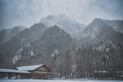 吹雪で視界不良の上高地バスターミナルと雪山の風景