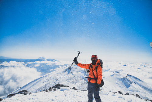 雪山の山頂で右手を振り上げる登頂の喜びを表現する登山者