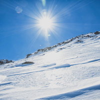 氷化した雪山の斜面と太陽に照らされた雲海の写真