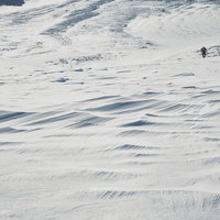 果てまで続くシュカブラと登山者の雪山の写真