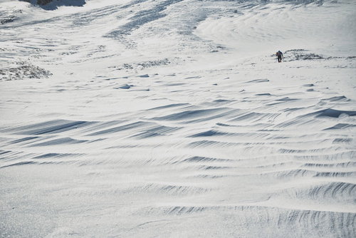 果てまで続くシュカブラと登山者の雪山