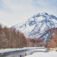 梓川の河畔を歩く登山者と雪化粧した穂高連峰（上高地）の写真