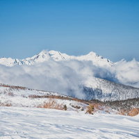 雲に巻かれる雪化粧の穂高連峰（飛騨山脈）の写真