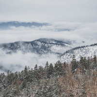 覆われた雲の中から顔を出す積雪した雪山の冬景色の写真