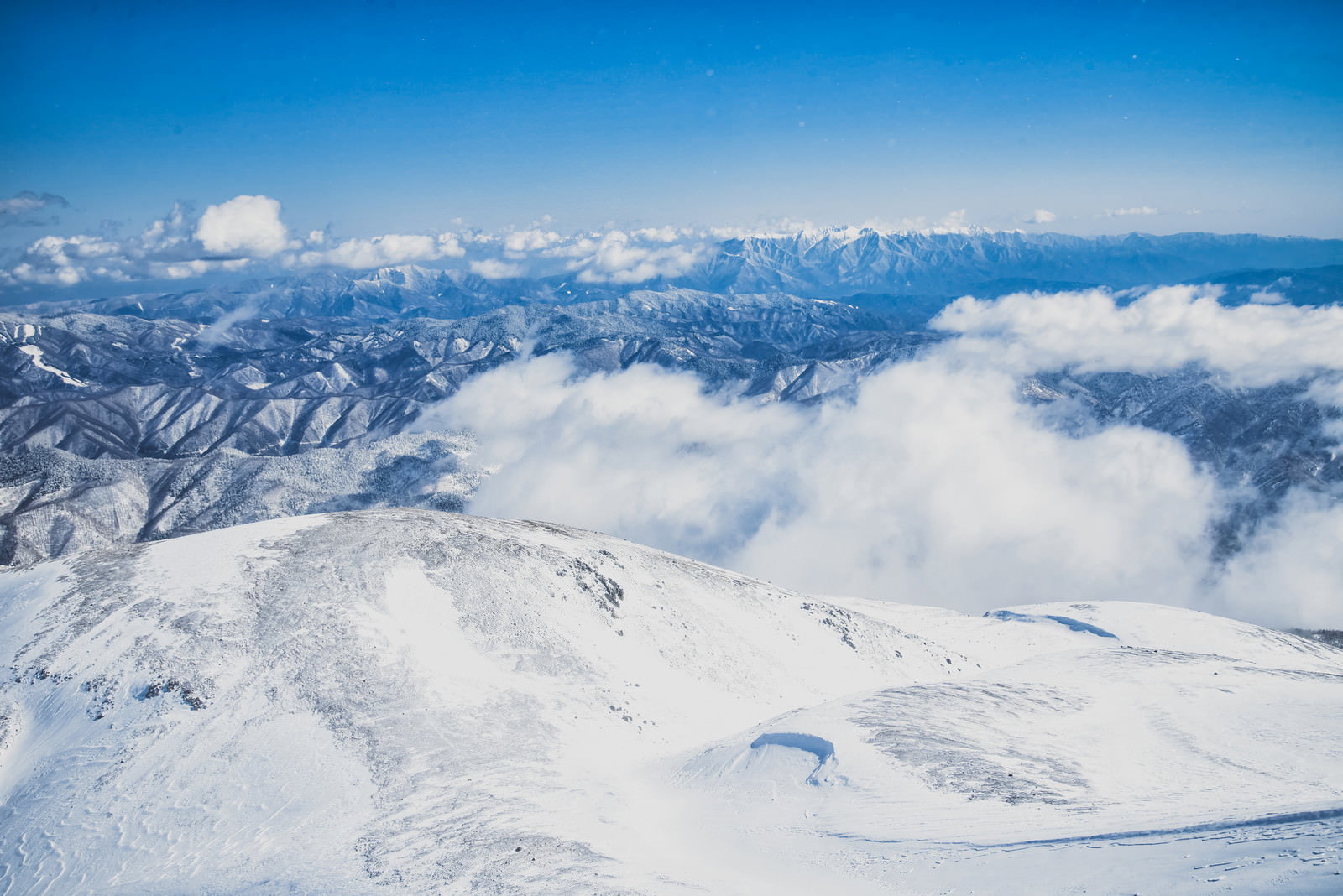 剣ヶ峰山頂から見下ろす雪に覆われた山々と雲海の絶景