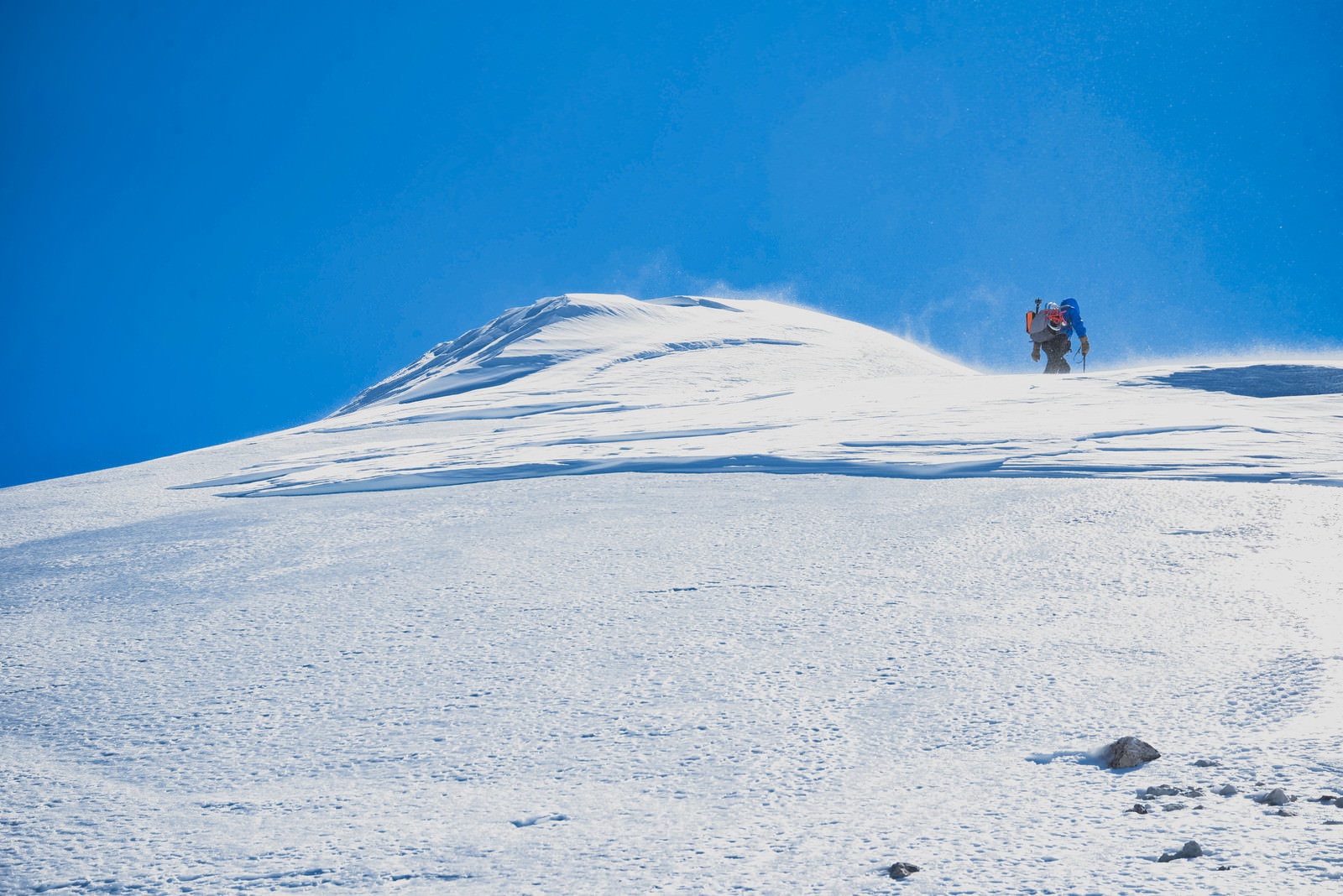 雪化粧した剣ヶ峰の山頂付近を歩く登山者と青空