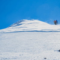 雪化粧した剣ヶ峰山頂を目指す登山者の冬山登山の写真