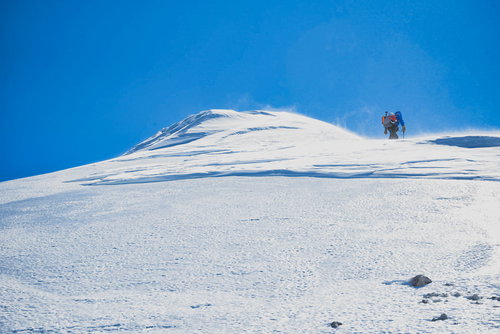雪化粧した剣ヶ峰山頂を目指す登山者の冬山登山
