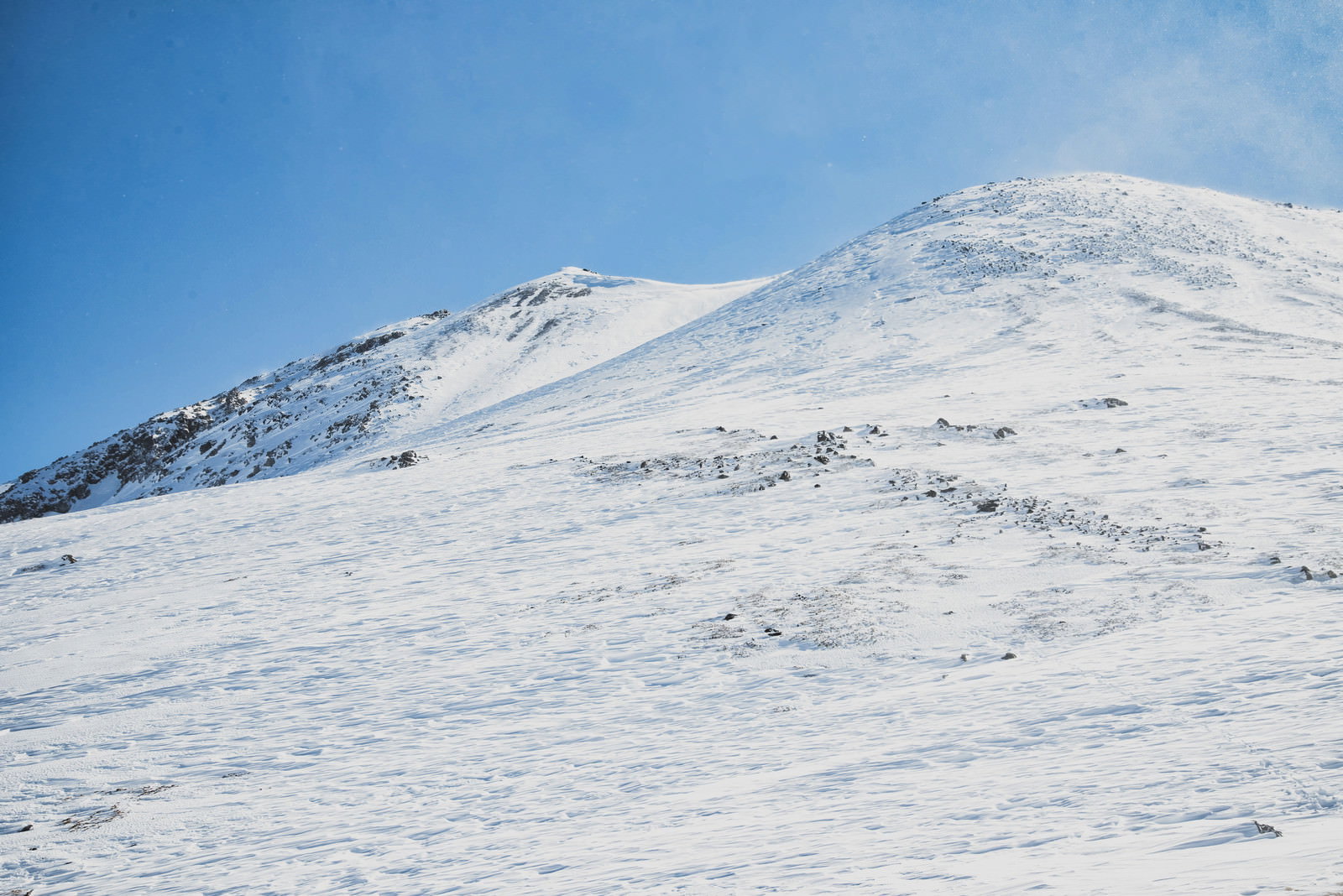 青空の下、雪化粧した北アルプスの朝日岳を山小屋から撮影した冬山風景