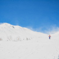 広大な冬の乗鞍高原を歩く登山者と北アルプスの風景の写真