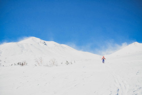 広大な冬の乗鞍高原を歩く登山者と北アルプスの風景