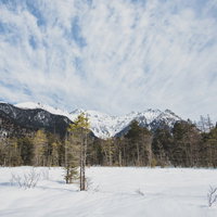上高地に広がる雪原と穂高連峰、広い青空、冬の山々の景観の写真