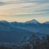 城山公園から見る夕焼けに染まる雪山と山脈の写真