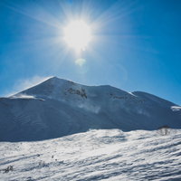 西日の太陽と雪化粧した剣ヶ峰の冬景色の写真