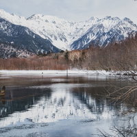 水面に反射した雪化粧の穂高連峰と大正池の冬景色の写真