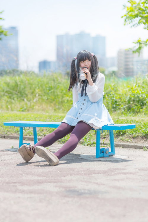 公園のベンチで紙コップを飲む女の子