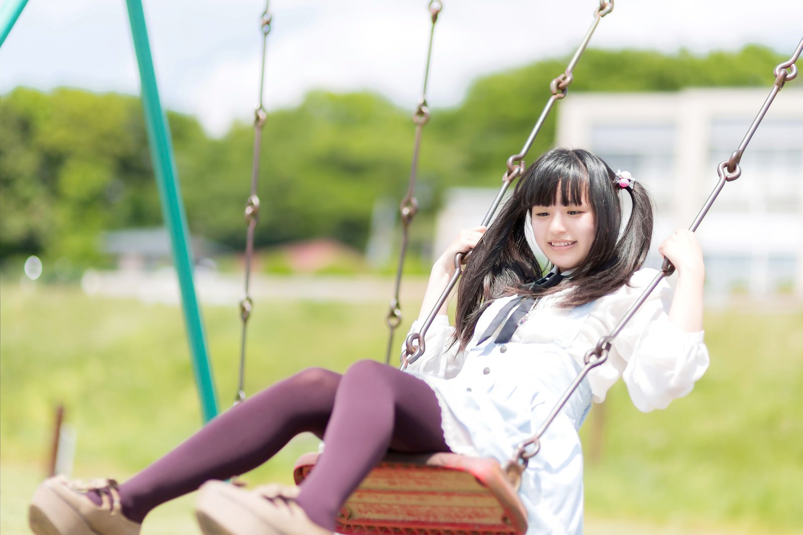 公園のブランコを漕ぐツインテールの女の子［モデル：こころ］
