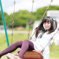 公園のブランコを漕ぐツインテールの女の子の写真