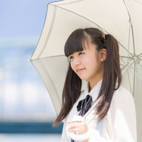 海辺で日傘をさすツインテールの女の子の写真
