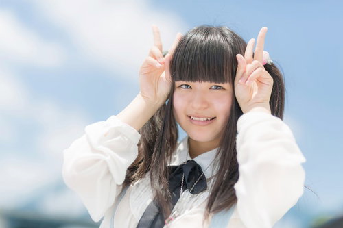 ピースサインで笑顔のツインテールの女の子