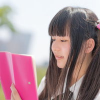 ピンクのノートを確認するツインテールの女の子の写真