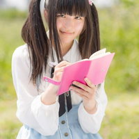 ピンクのノートに書き込むツインテールの女の子の写真