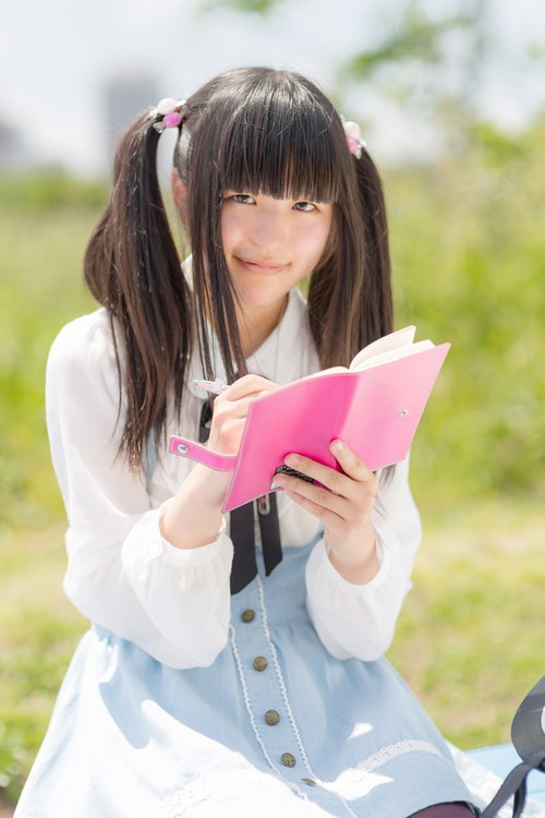 ピンクのノートに書き込むツインテールの女の子