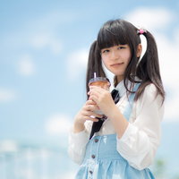 青空の下でツインテールの女の子がドリンクを片手に休憩の写真