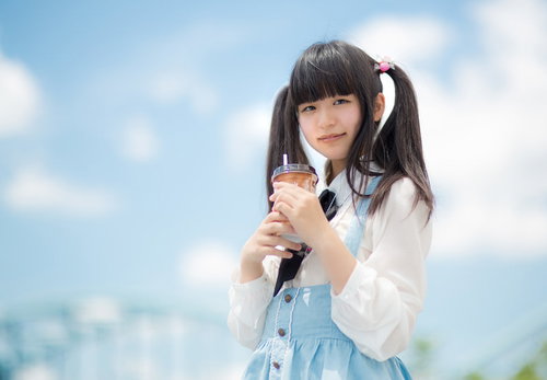 青空の下でツインテールの女の子がドリンクを片手に休憩