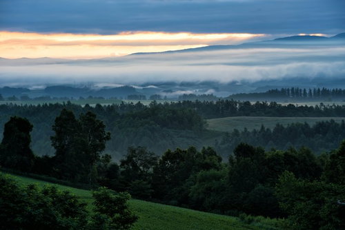 北海道の高台から見る朝焼けと朝霧に包まれた山々の風景