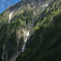 雪化粧した滝沢断崖の岩壁と深い谷間の冬山景観の写真