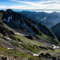 涸沢カールの岩壁と残雪が残る登山道の写真