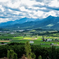富良野の山の麓に広がる緑の平野と田舎町の風景の写真