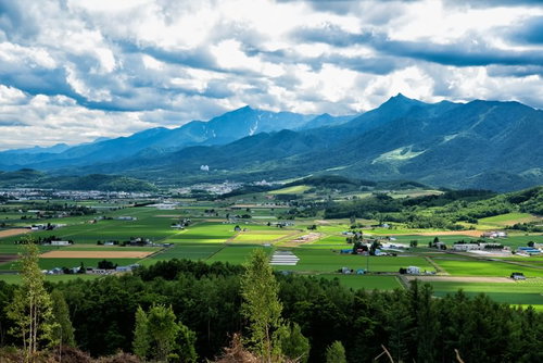富良野の山の麓に広がる緑の平野と田舎町の風景