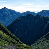 快晴の常念岳の山稜景色、深い谷間と重なり合う山々のシルエットの写真