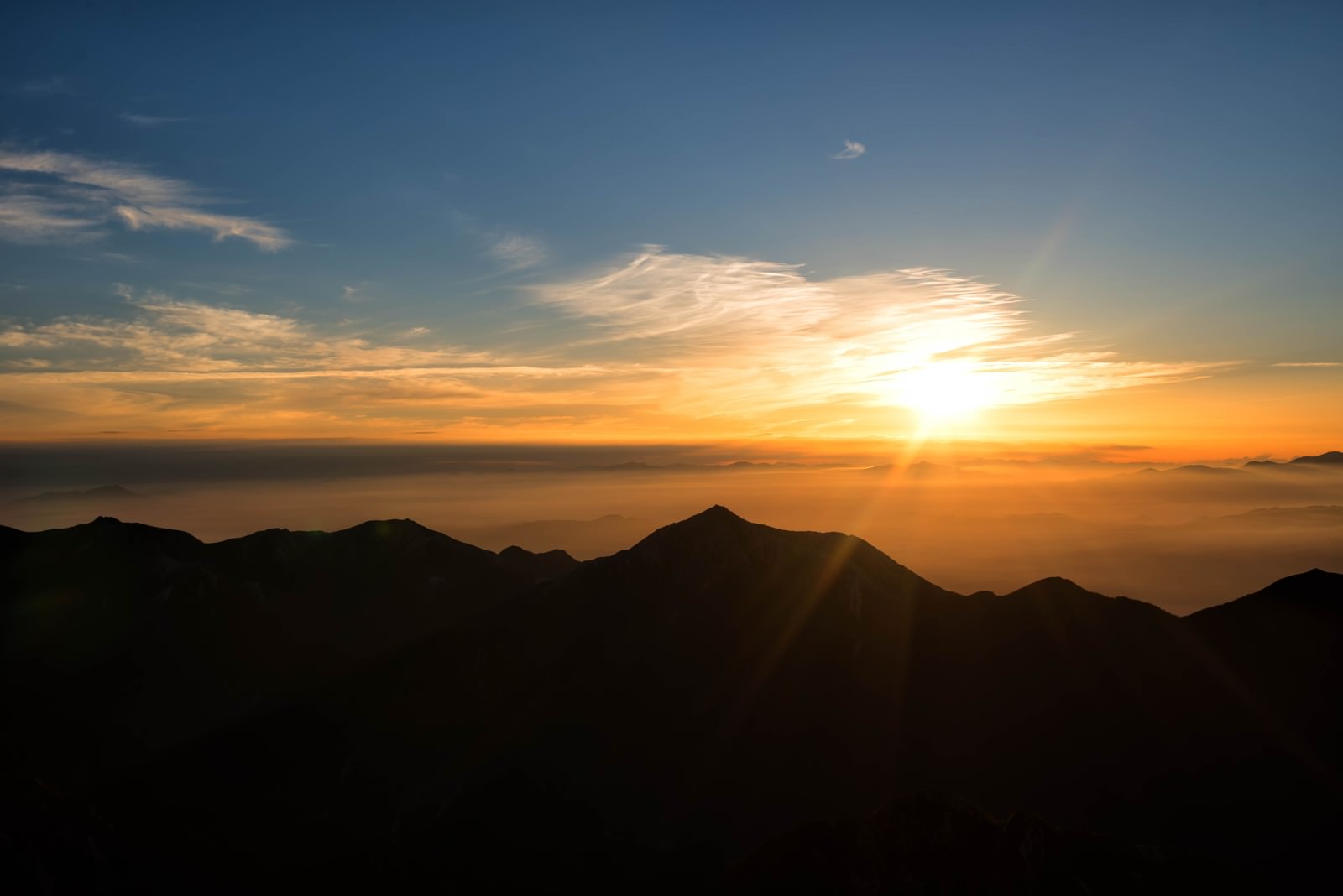 常念山脈のシルエットと朝焼けに染まった空に昇る太陽