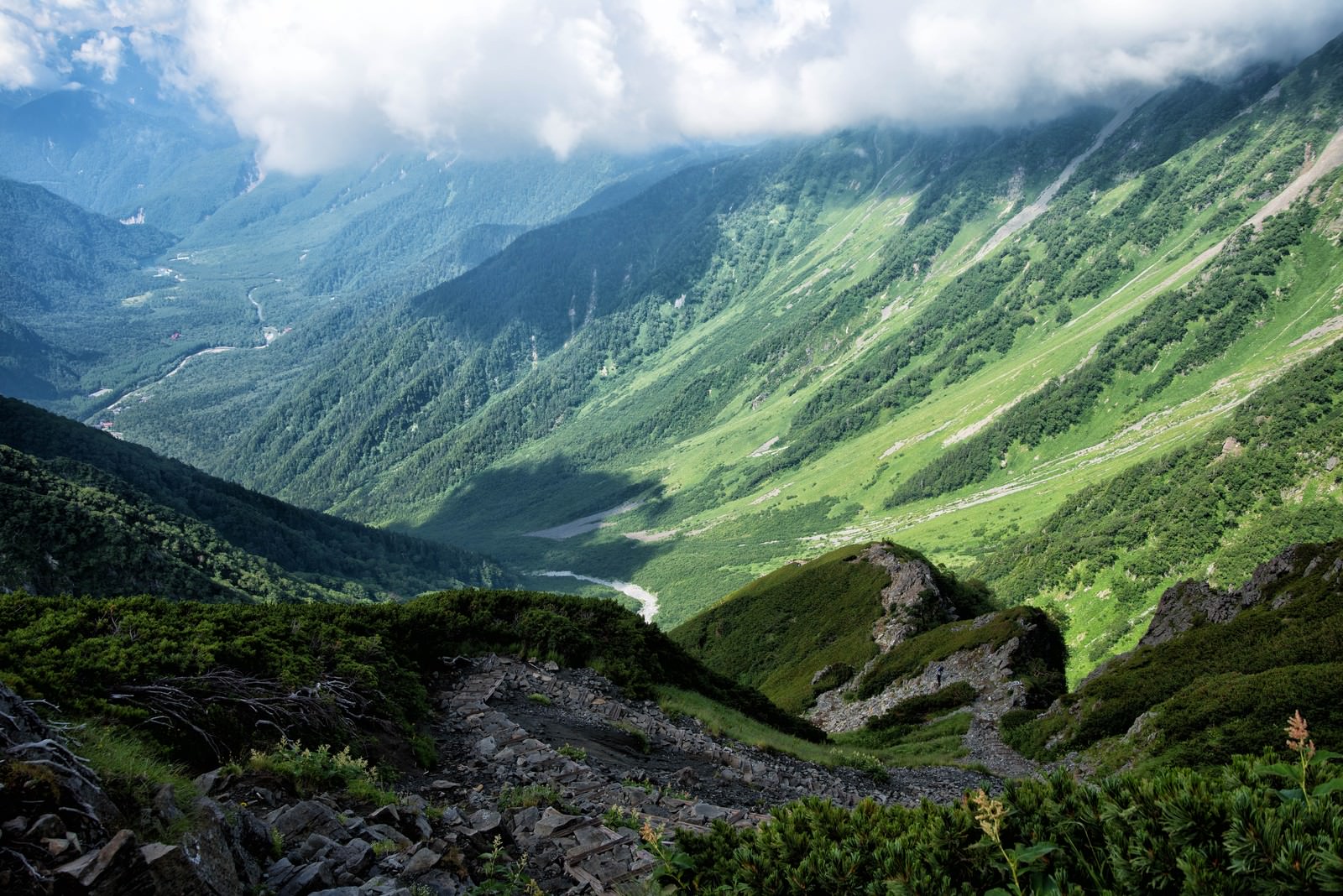 重太郎新道から見える緑の山々とガレ場の登山道、空に浮かぶ白い雲