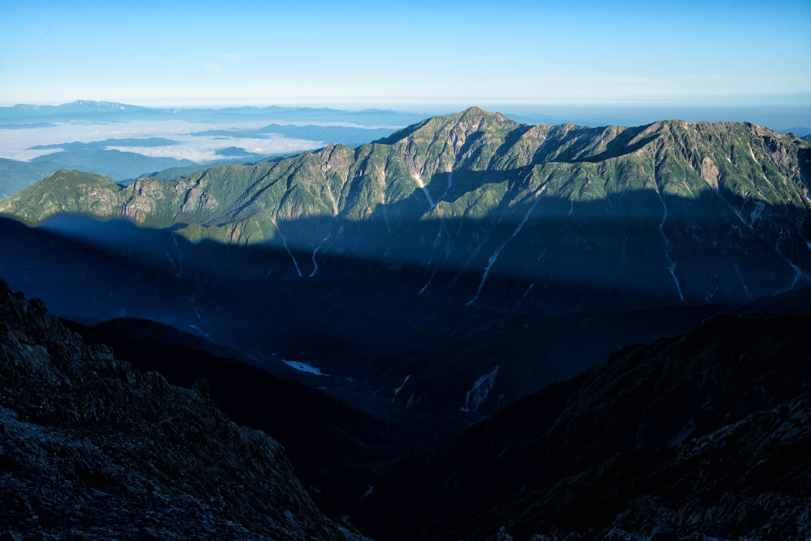 朝焼けの光に照らされた笠ヶ岳の雄大な山々と深い谷間の風景