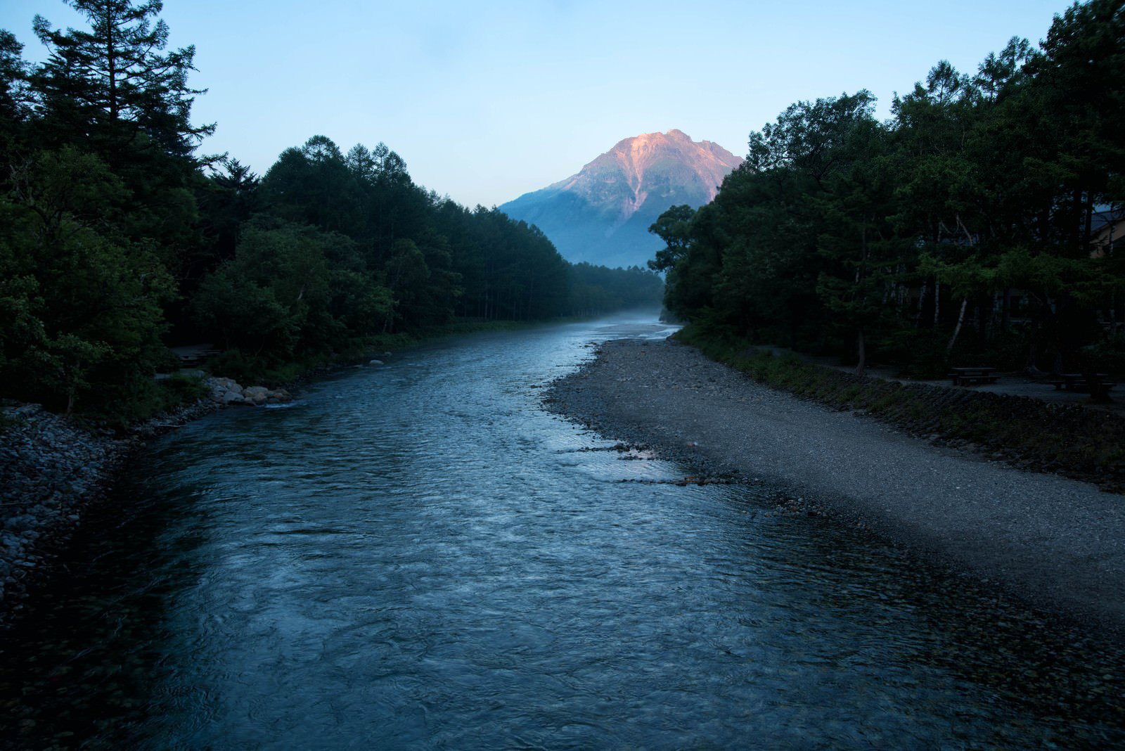 朝焼けの光に照らされた梓川と背景に見える焼岳の風景