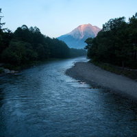 朝焼けに染まる焼岳に続く梓川の静観と朝霧の風景の写真