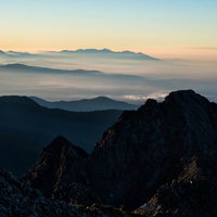 朝焼けに染まる八ヶ岳と前穂高岳の雲海と山並みの写真