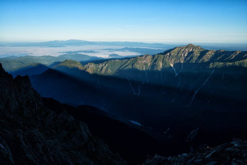 穂高から伸びる影と笠ヶ岳の尾根を望む山岳風景