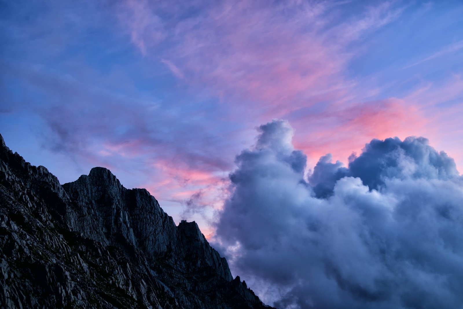 夕焼け空に白い積雲が沸き立ち、ジャンダルムの険しい岩峰がシルエットで写る山岳風景