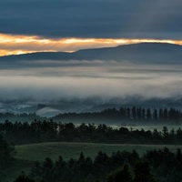 朝霧に包まれる美瑛町の丘陵地帯の朝焼けと雲海の写真