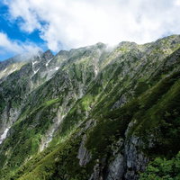 雲が沸き立つ吊尾根の岩壁と山岳風景の写真